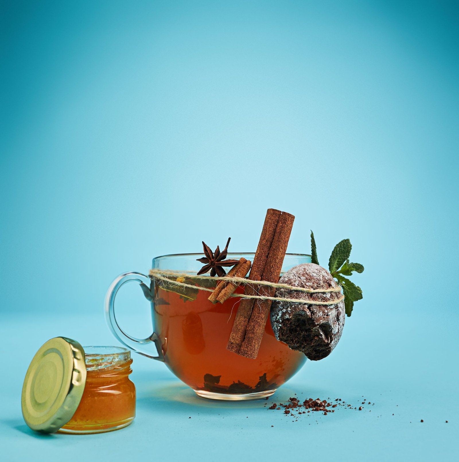 The conceptual image of cup of herbal tea, honey, cake on a blue background